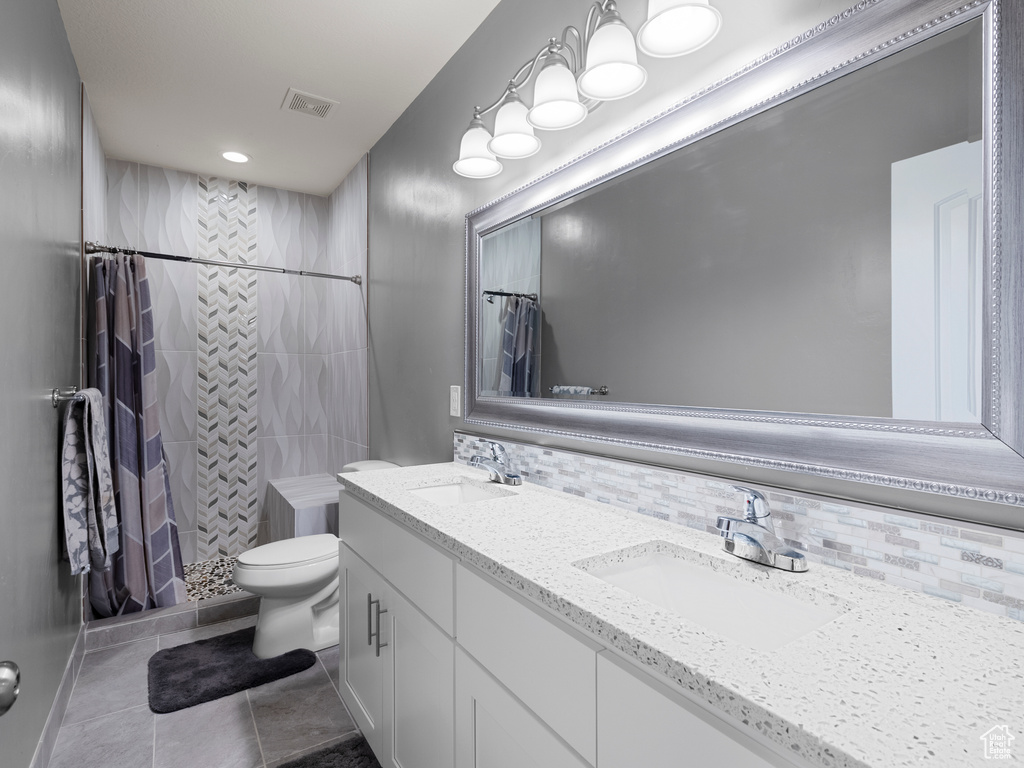 Full bath with toilet, tiled shower, decorative backsplash, and tile patterned floors