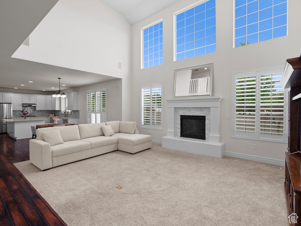 Living area with a glass covered fireplace, a chandelier, wood finished floors, recessed lighting, and baseboards