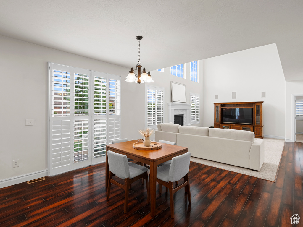 Dining space with a chandelier, wood finished floors, baseboards, and a fireplace