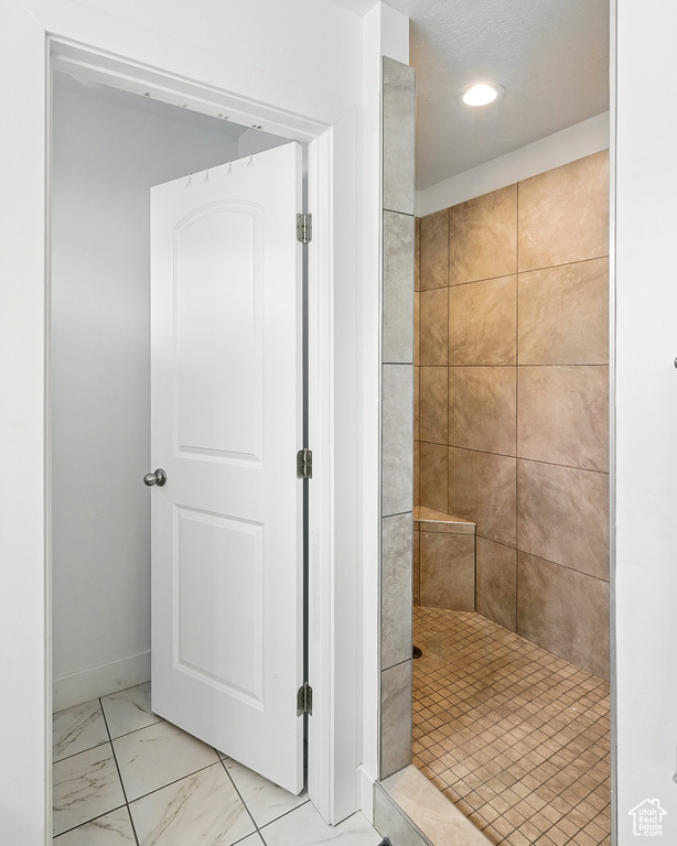 Bathroom with a tile shower, marble finish flooring, and recessed lighting