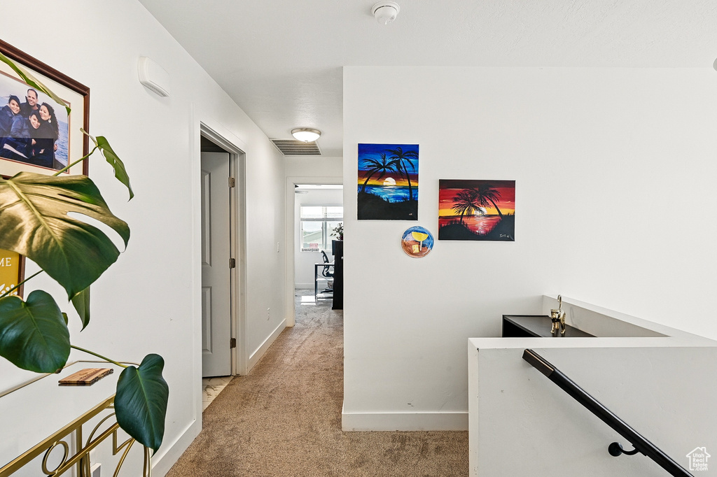 Hall featuring an upstairs landing, light colored carpet, and baseboards