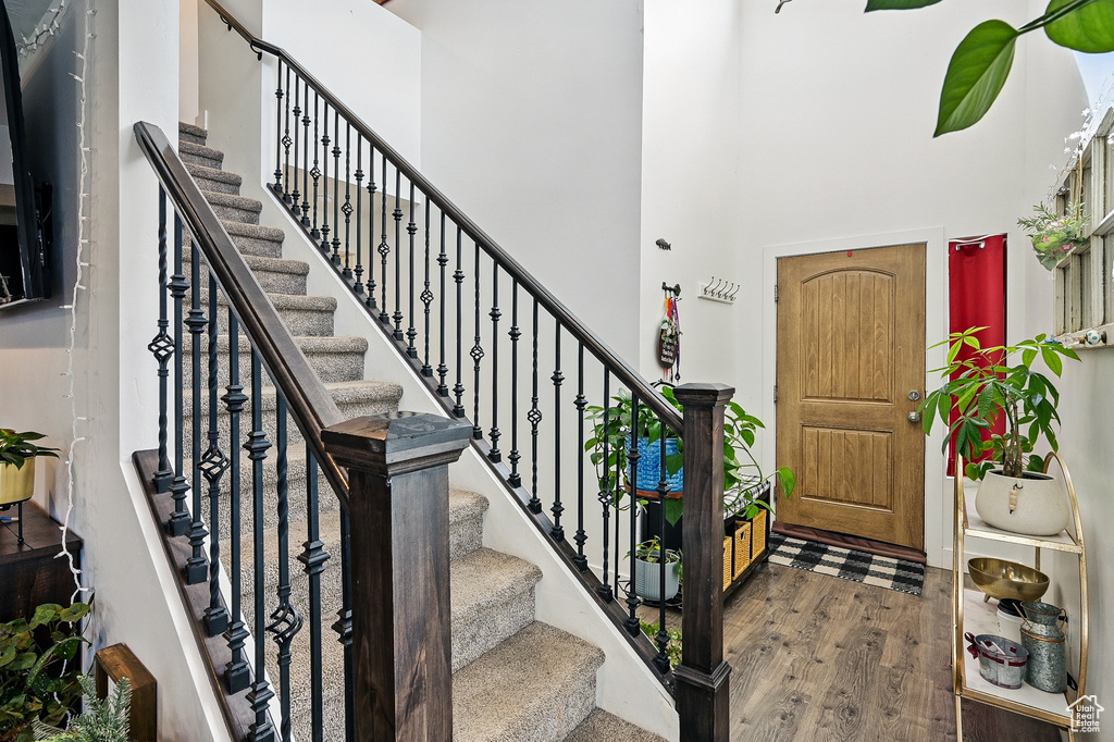 Foyer with a towering ceiling, wood finished floors, and stairway