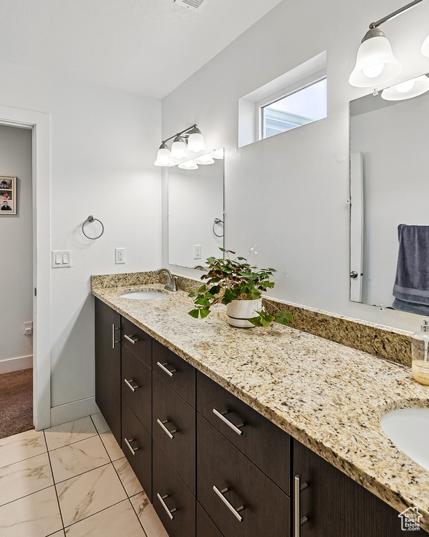 Bathroom featuring vanity, marble look tiles, and baseboards