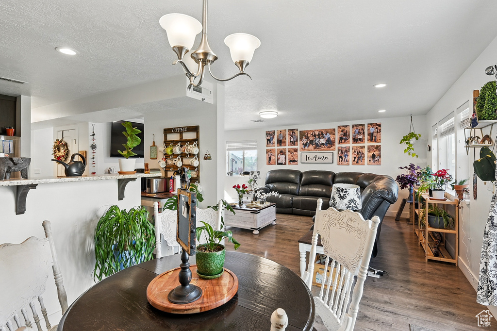 Dining space with healthy amount of natural light, wood finished floors, recessed lighting, and a chandelier