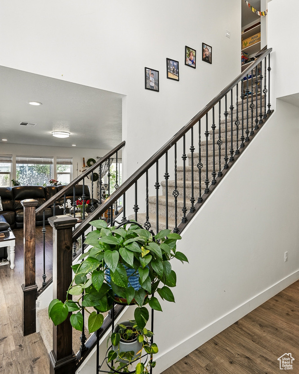 Staircase featuring wood finished floors, baseboards, and recessed lighting
