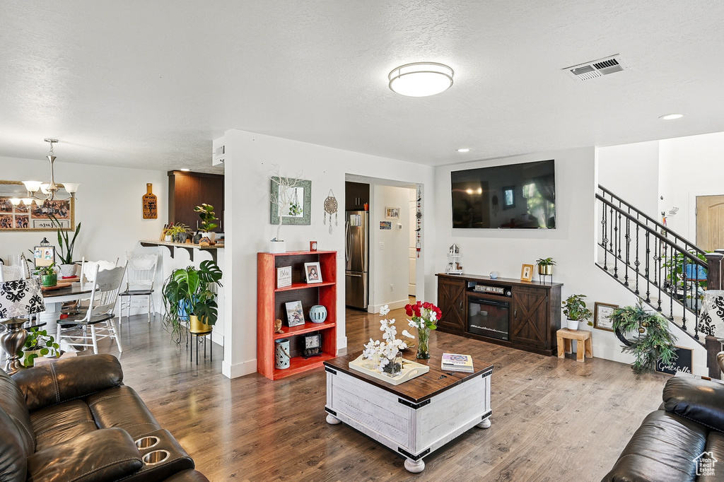 Living area featuring wood finished floors, a chandelier, stairway, baseboards, and recessed lighting