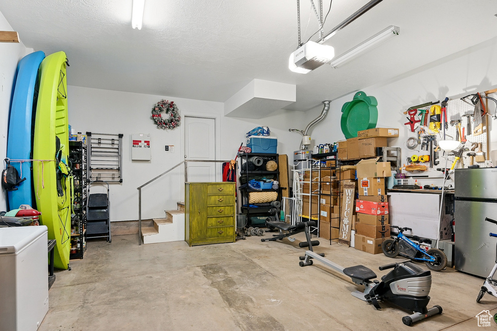 Garage featuring a garage door opener and freestanding refrigerator