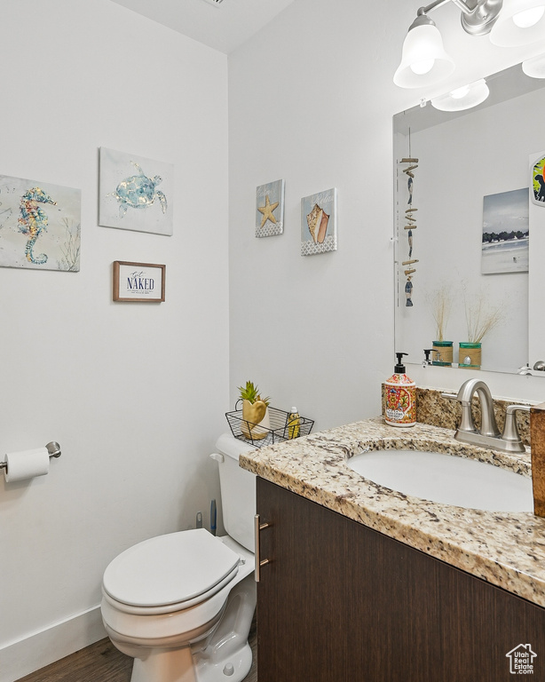 Bathroom with vanity, toilet, wood finished floors, and baseboards