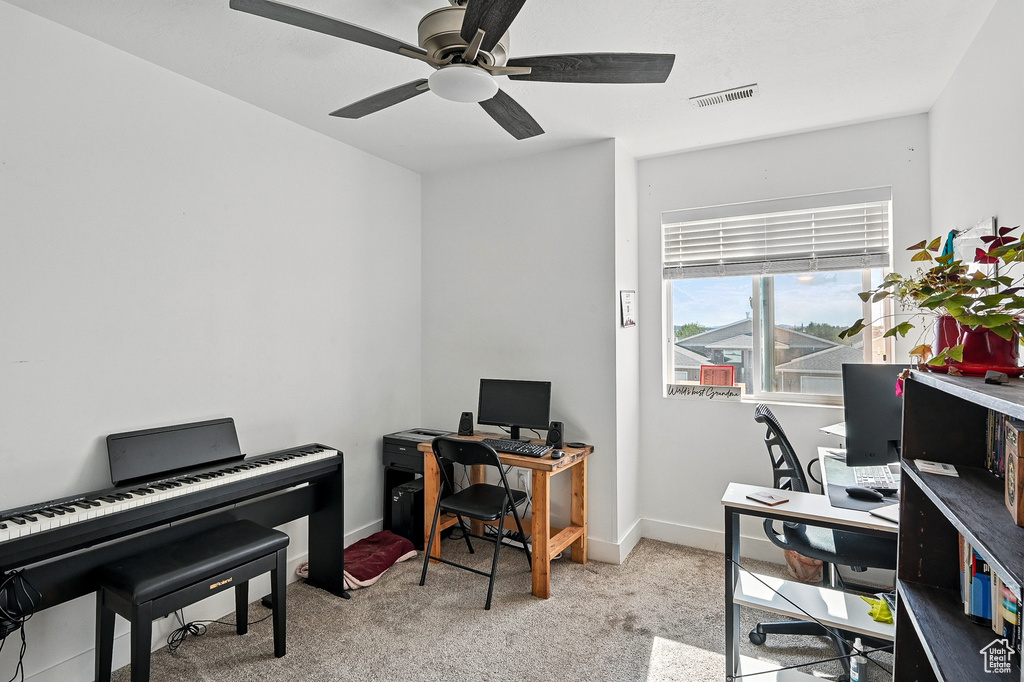 Carpeted home office featuring a ceiling fan and baseboards