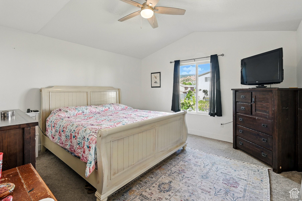 Bedroom featuring lofted ceiling, light colored carpet, baseboards, and a ceiling fan