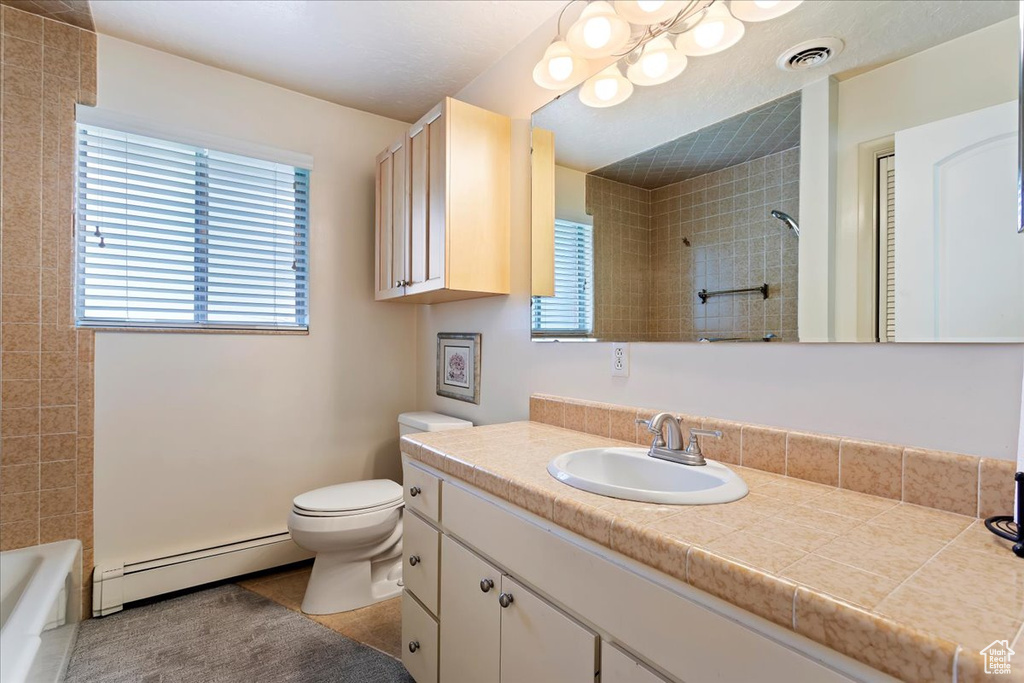 Bathroom featuring a baseboard radiator, toilet, tile patterned floors, and vanity