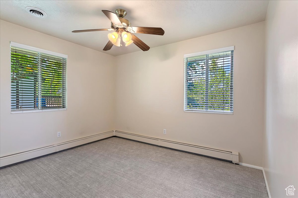 Carpeted spare room with a ceiling fan and baseboards