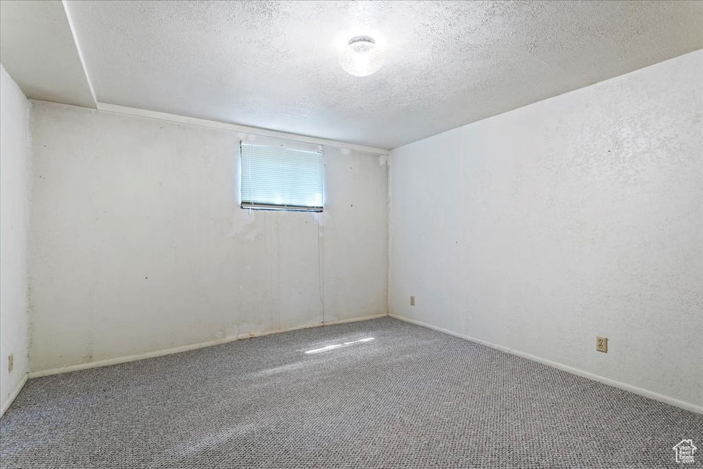 Carpeted empty room with a textured ceiling and baseboards