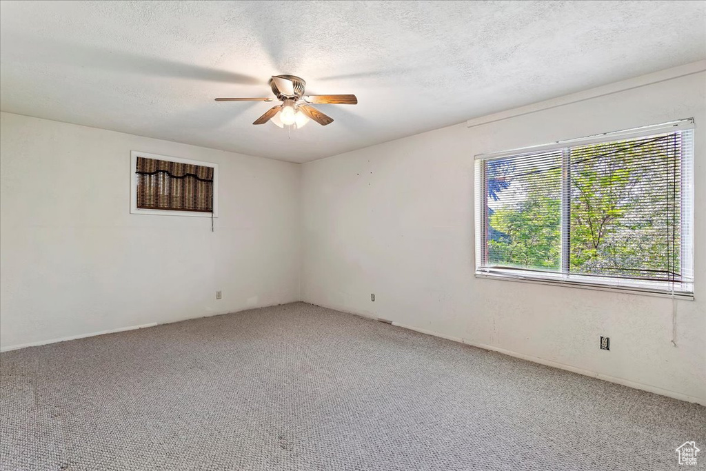Unfurnished room with ceiling fan, light colored carpet, and a textured ceiling