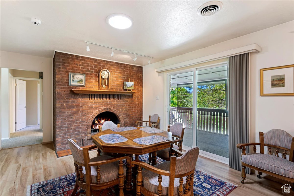 Dining room featuring a fireplace, rail lighting, and light wood-type flooring