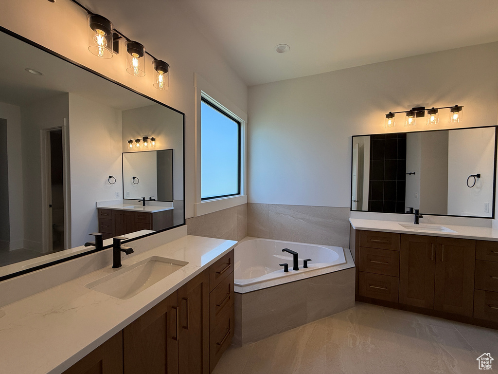 Bathroom featuring a bath, two vanities, and tile patterned floors
