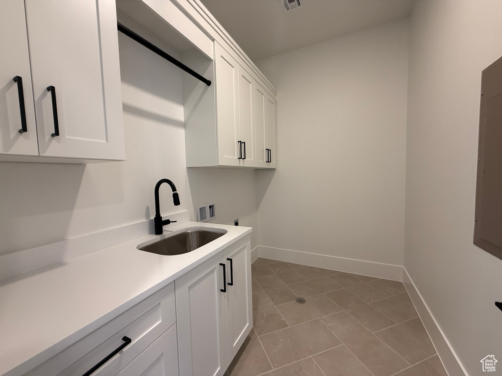 Washroom with cabinet space, washer hookup, hookup for an electric dryer, baseboards, and light tile patterned floors