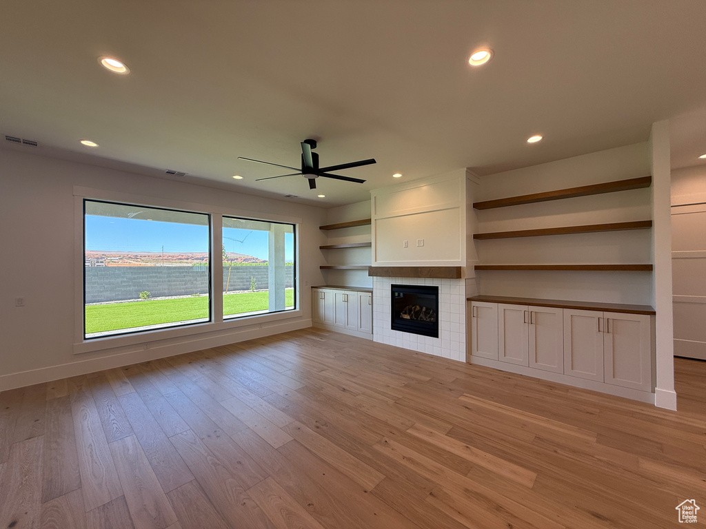 Unfurnished living room featuring a ceiling fan, light wood finished floors, recessed lighting, baseboards, and a fireplace