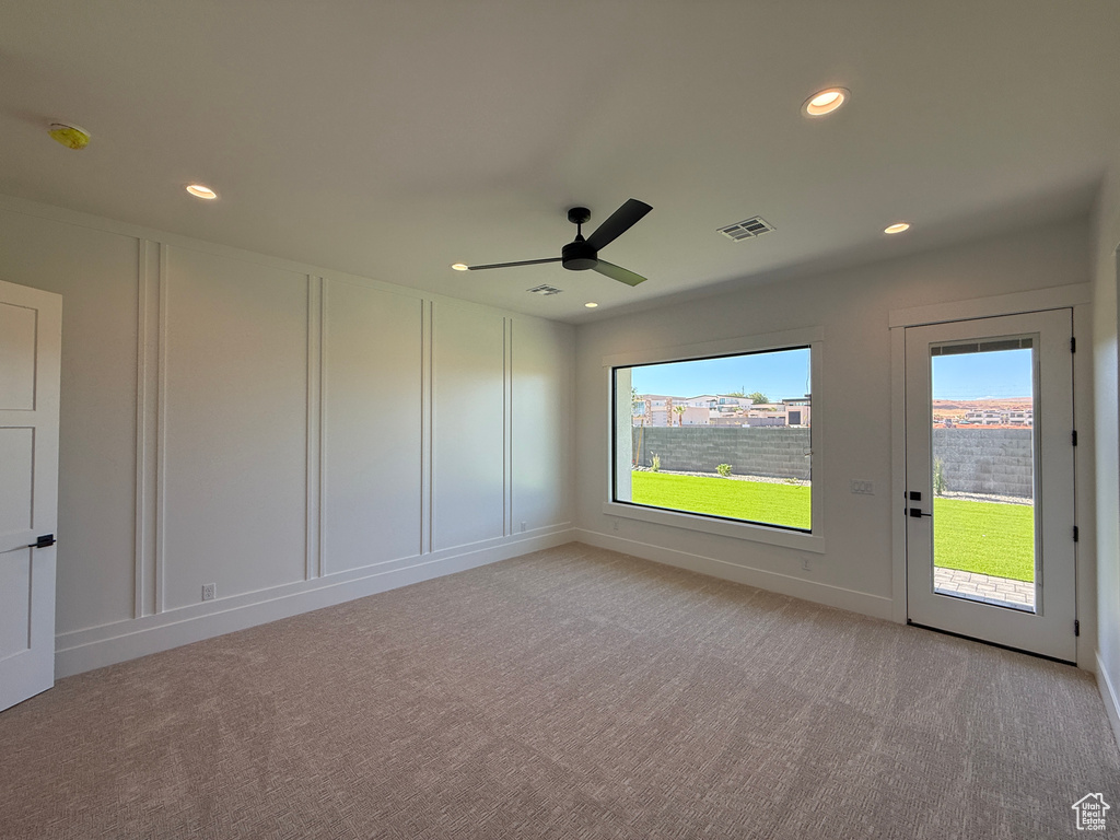 Unfurnished room with plenty of natural light, light carpet, ceiling fan, recessed lighting, and a decorative wall