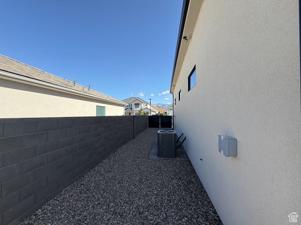 View of side of property with fence, stucco siding, and central AC unit
