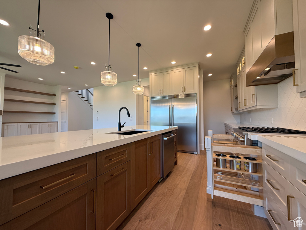 Kitchen featuring appliances with stainless steel finishes, exhaust hood, a sink, decorative backsplash, and recessed lighting