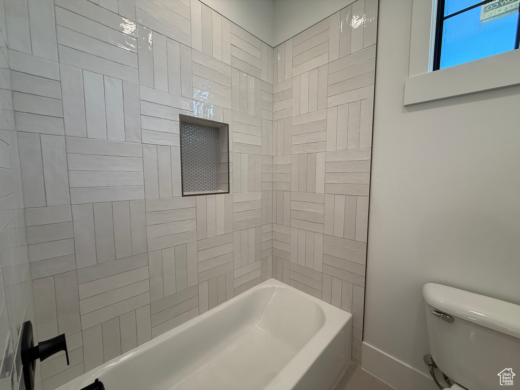 Bathroom with toilet, baseboards, and bathing tub / shower combination