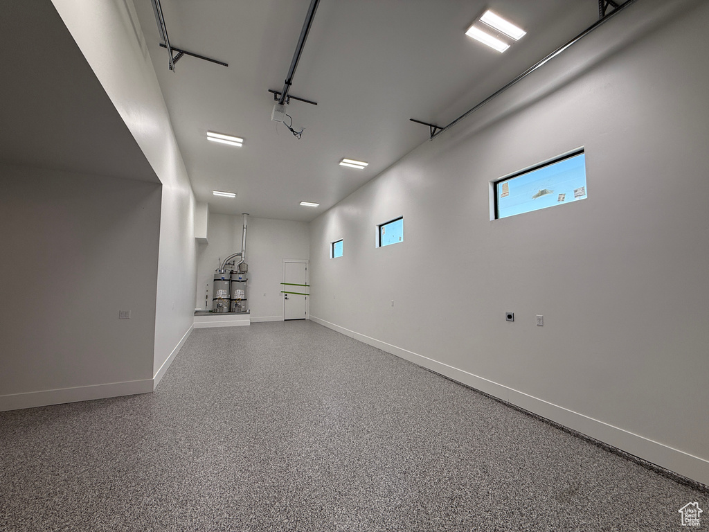 Basement with a garage, baseboards, and strapped water heater