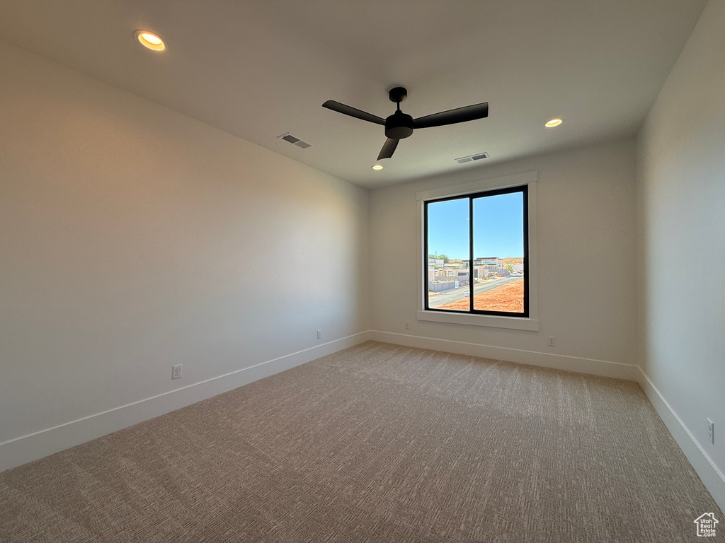 Empty room featuring light carpet, ceiling fan, baseboards, and recessed lighting