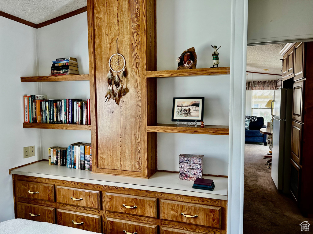 Detailed view of a textured ceiling, carpet flooring, and crown molding
