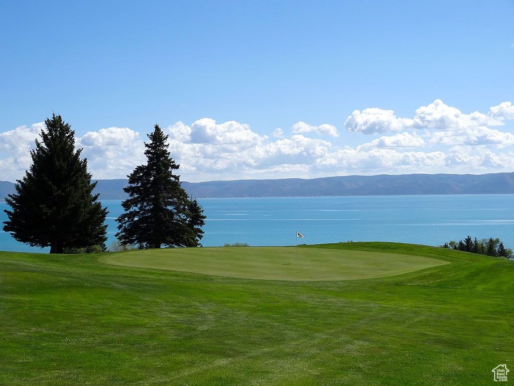 Surrounding community featuring a water and mountain view, view of golf course, and a yard