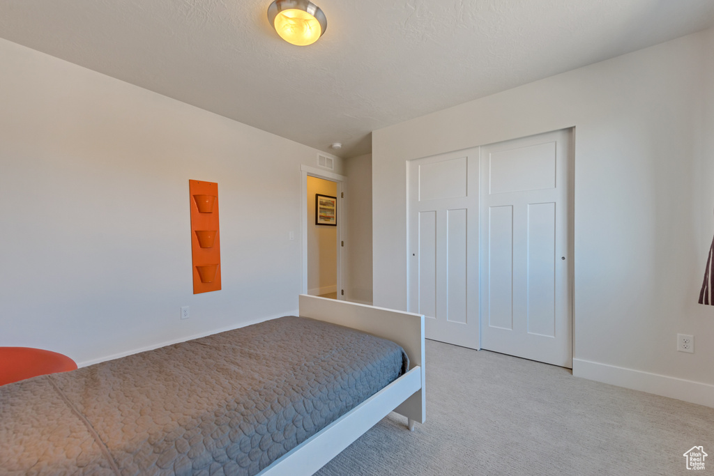 Bedroom with light carpet, baseboards, and a closet
