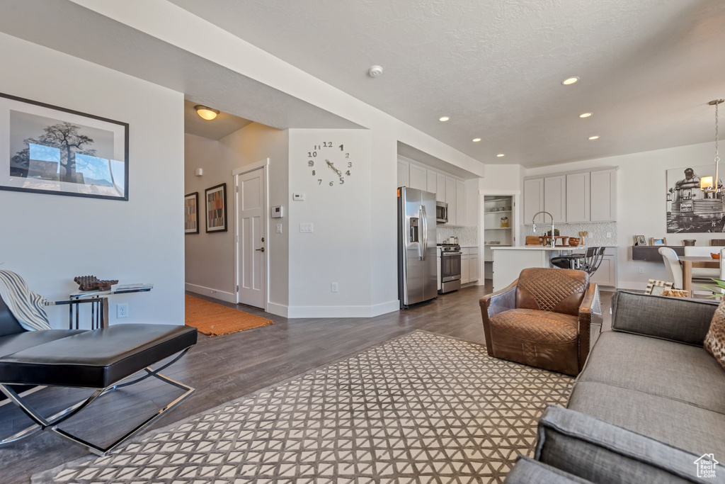 Living area with dark wood finished floors, recessed lighting, a chandelier, and baseboards