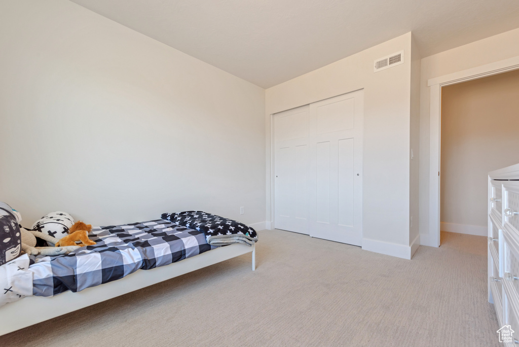 Bedroom featuring light colored carpet, baseboards, and a closet