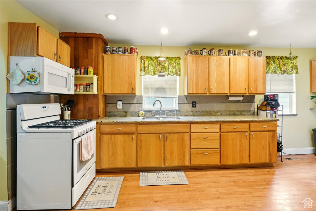 Kitchen featuring white appliances, a sink, plenty of natural light, light wood-style floors, and recessed lighting
