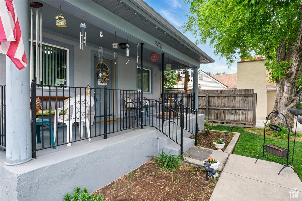 Entrance to property featuring covered porch and fence