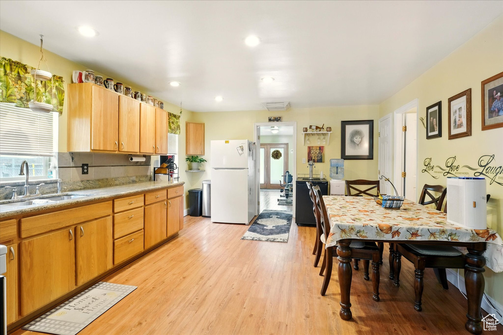 Kitchen featuring freestanding refrigerator, a sink, light wood-style flooring, light countertops, and recessed lighting