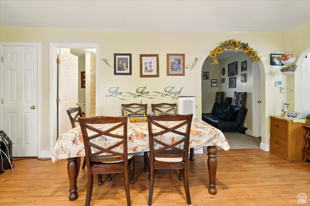 Dining room with light wood-type flooring, arched walkways, and baseboards