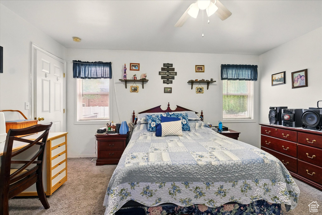 Bedroom featuring light colored carpet, multiple windows, and a ceiling fan