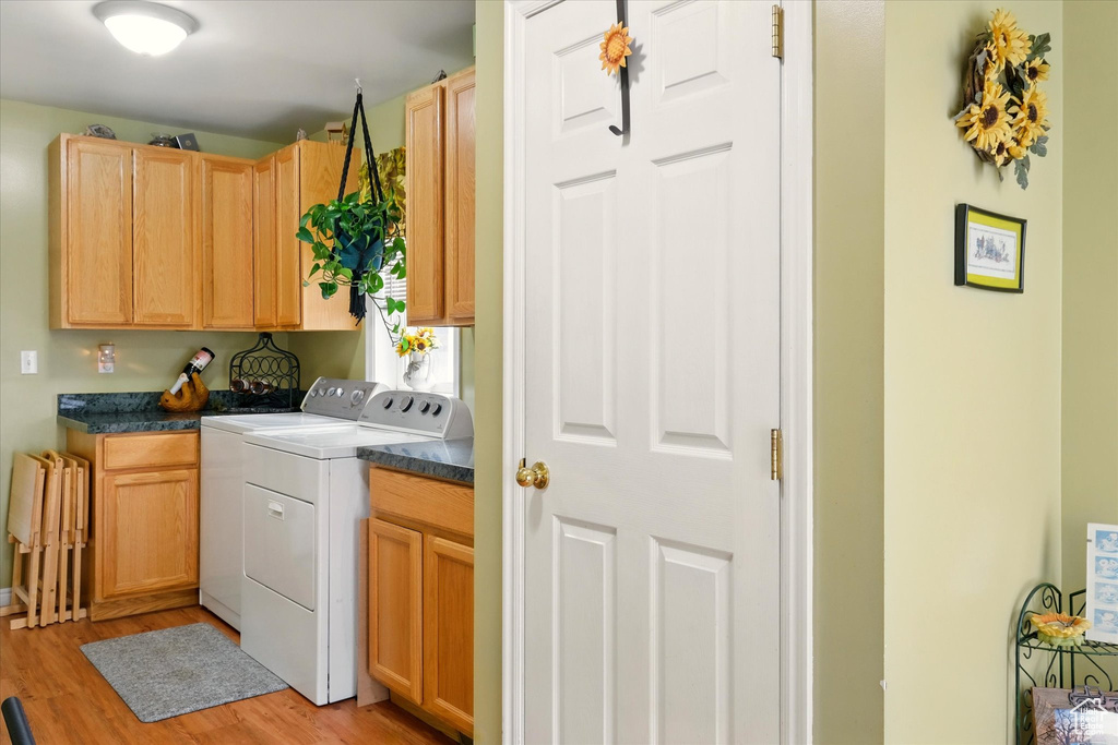 Laundry area with cabinet space, light wood-style floors, and separate washer and dryer