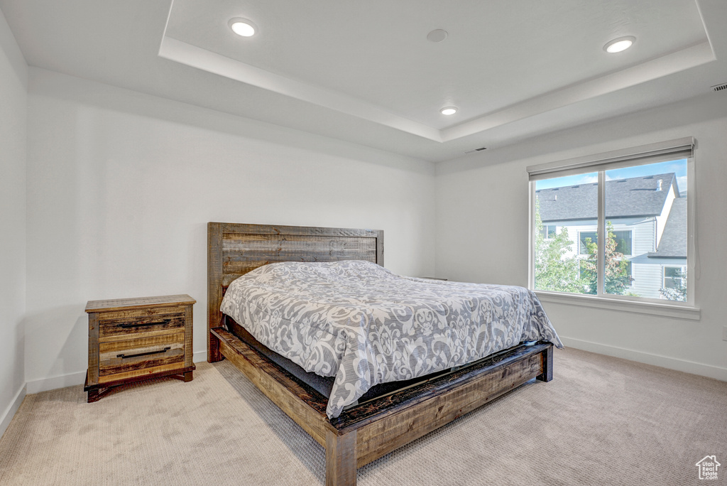 Carpeted bedroom featuring a raised ceiling, baseboards, and recessed lighting