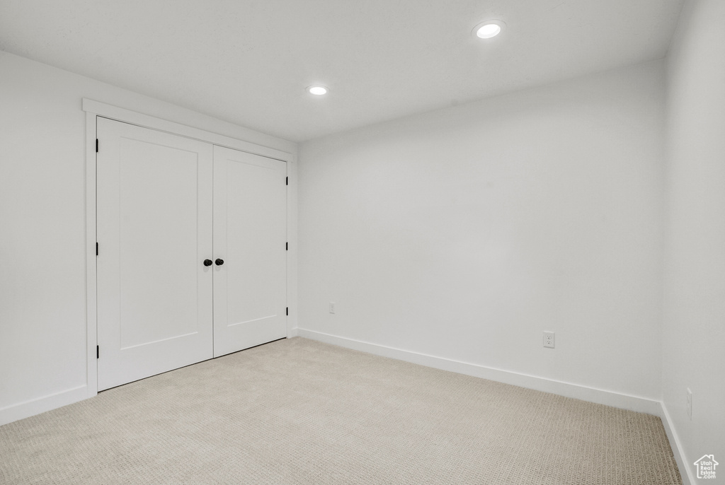Unfurnished bedroom with light colored carpet, baseboards, recessed lighting, and a closet