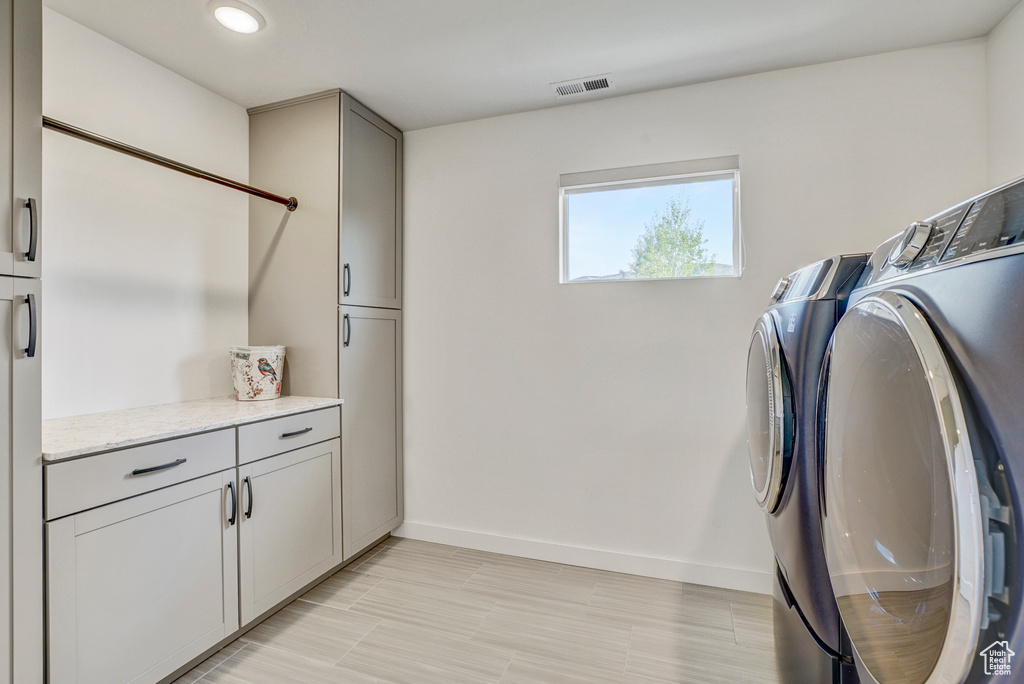 Clothes washing area featuring cabinet space, washer and clothes dryer, baseboards, and recessed lighting