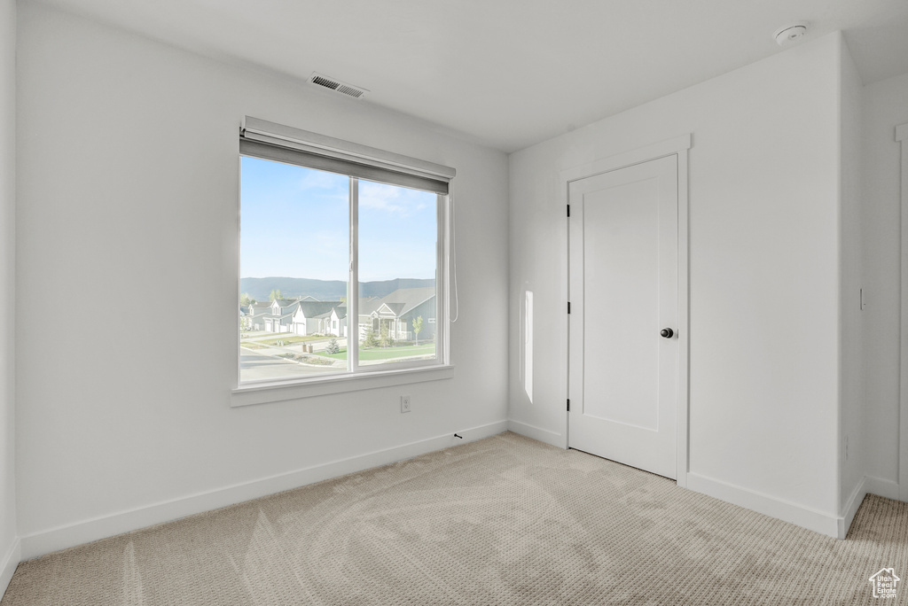 Unfurnished bedroom with light colored carpet and baseboards