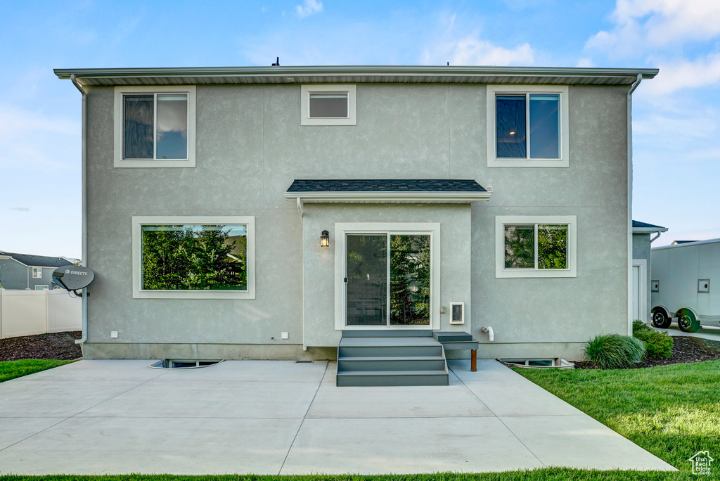Rear view of property with stucco siding, a patio area, entry steps, and a yard