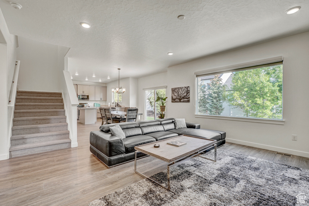 Living area with stairs, light wood-type flooring, recessed lighting, a textured ceiling, and baseboards