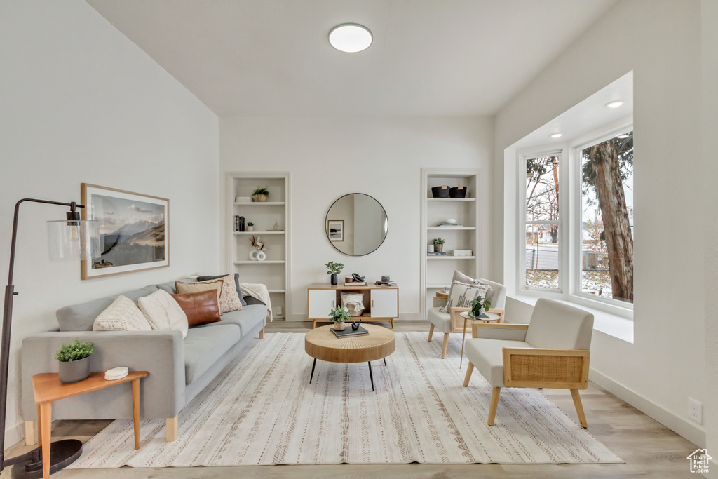 Living area with built in features, wood finished floors, and baseboards