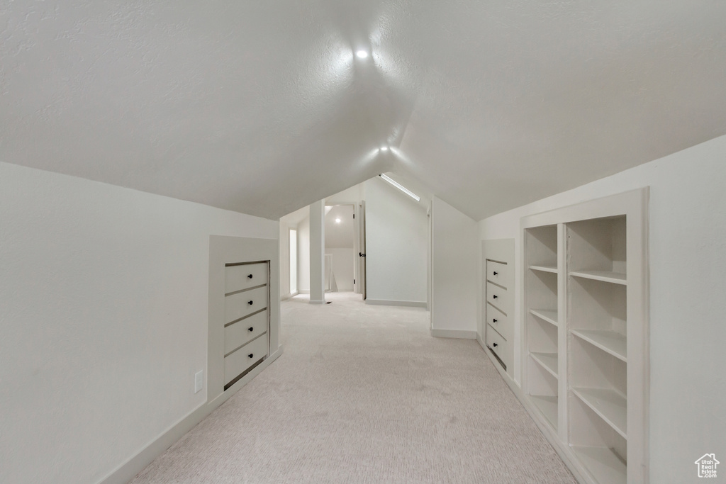 Bonus room with lofted ceiling, light colored carpet, and baseboards