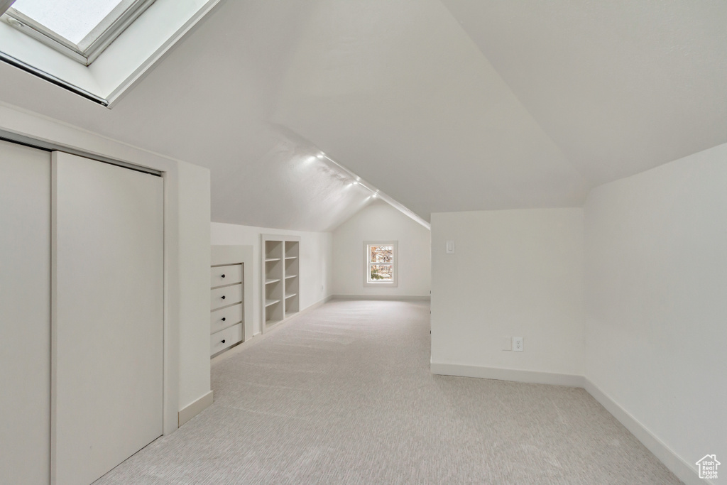 Bonus room featuring lofted ceiling, carpet flooring, a skylight, built in features, and baseboards