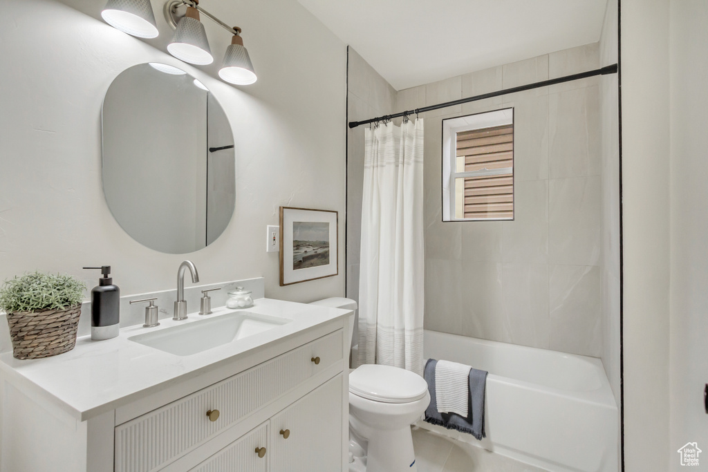 Full bath with toilet, shower / bath combo with shower curtain, and vanity