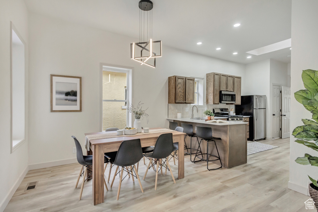 Dining room featuring light wood-style flooring, recessed lighting, baseboards, and a chandelier